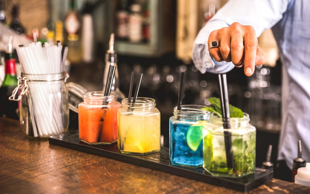 Manos de barman con bebidas coloridas.